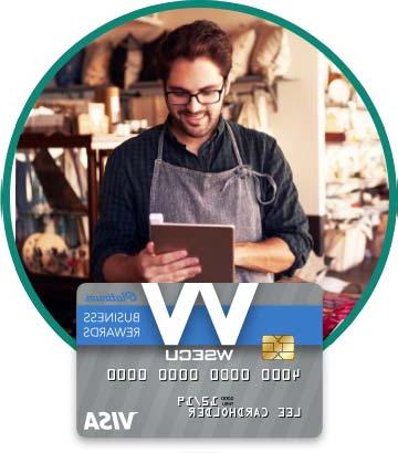 Store owner in apron holding tablet. Image of WSECU Platinum 业务 Rewards 签证 card below. 